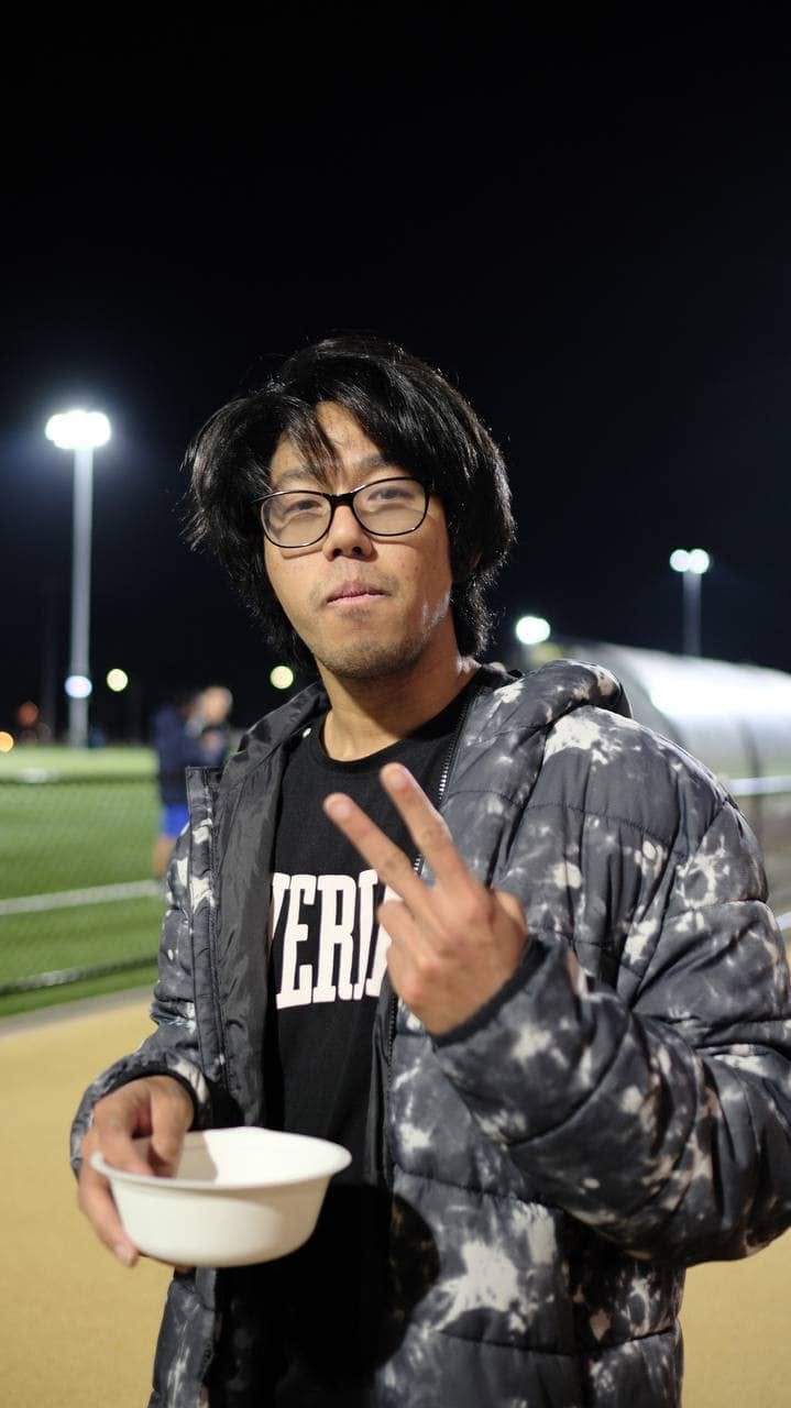 Player with glasses and a puffer jacket holding a bowl and a peace sign