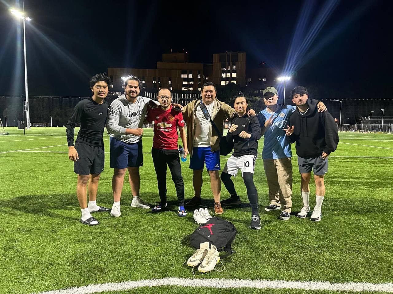 Eight players posing together under bright floodlights