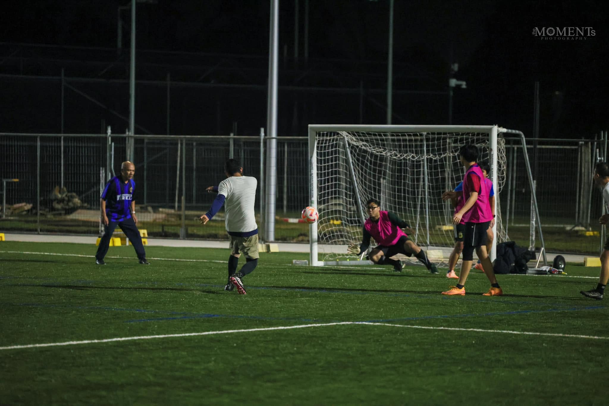A goalkeeper diving at a shot while an older player in an Inter shirt watches
