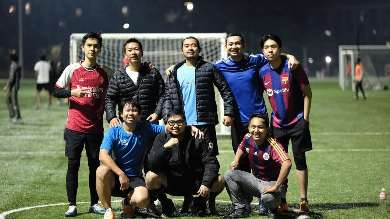 Seven friends grouped in front of the goal at night