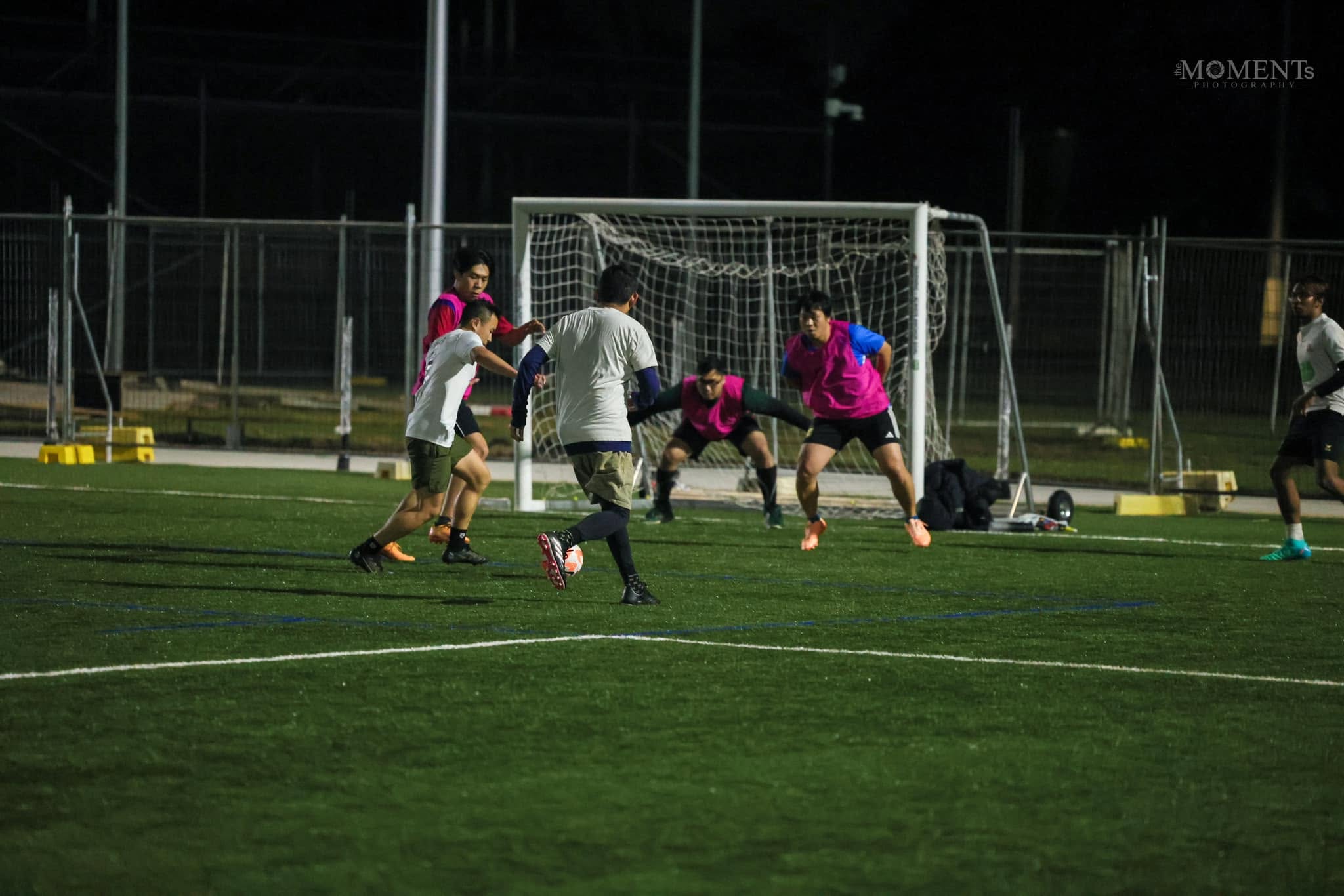 Two attackers dribbling past a defender toward a crowded goal