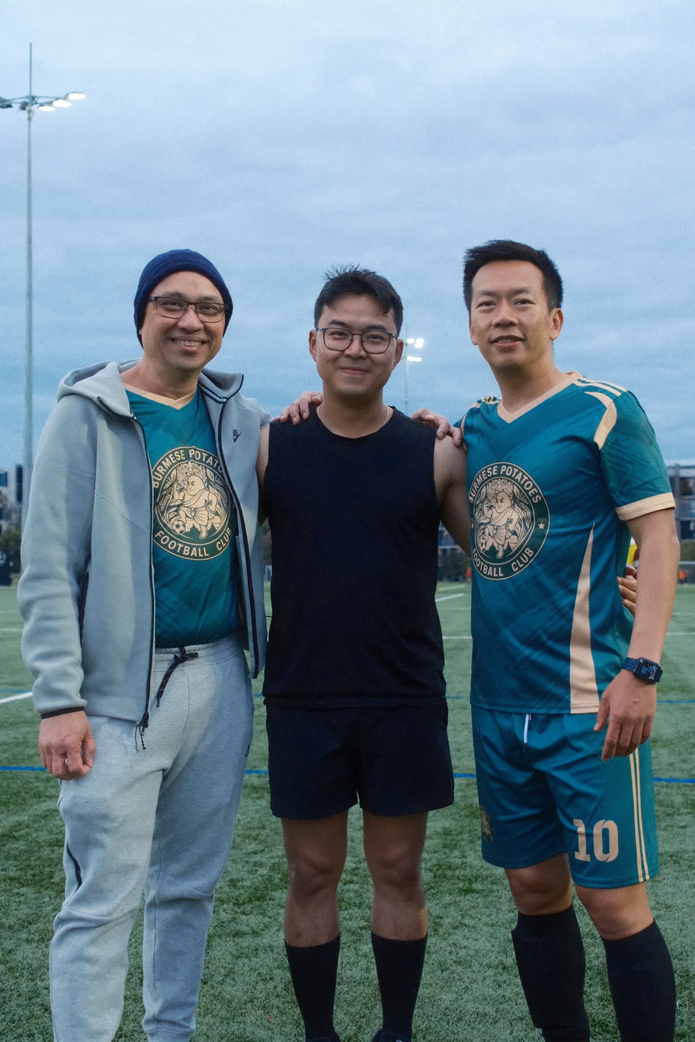 Three friends posing after the game, one in a teal number 10 shirt