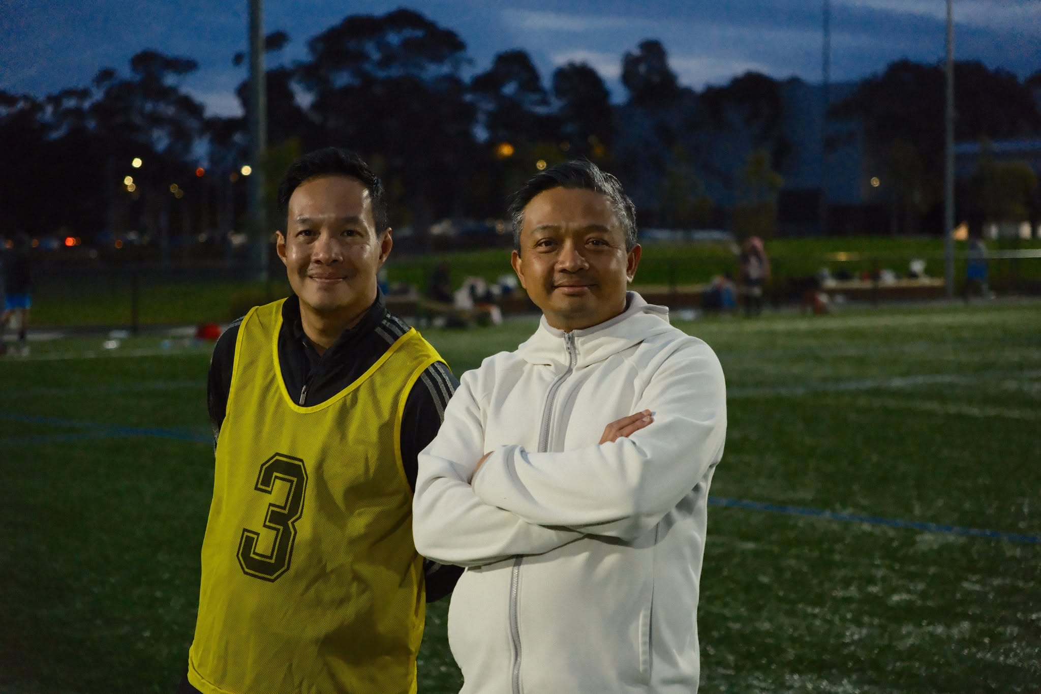 Two friends at dusk, one in a yellow number 3 bib