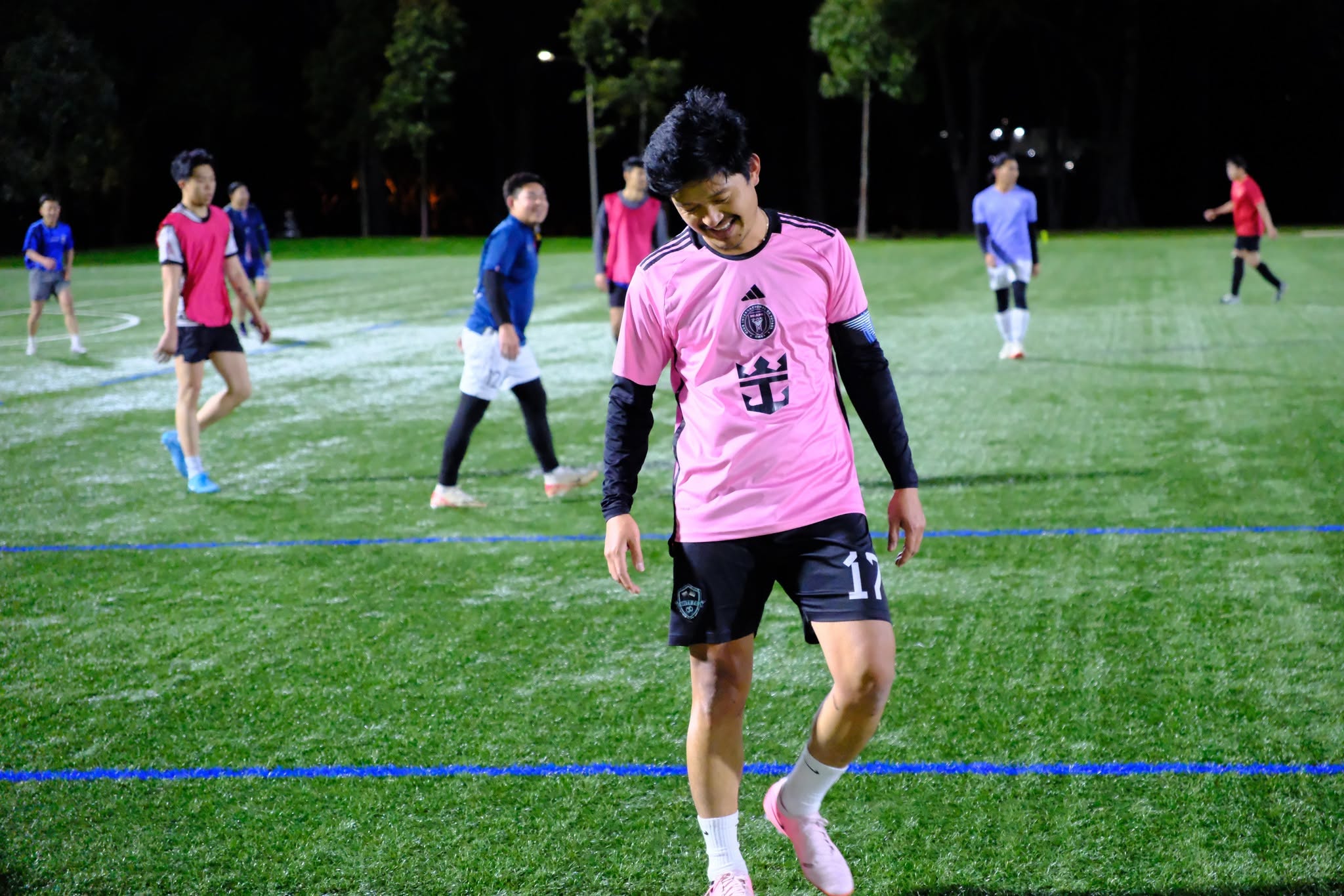 A player in a pink shirt dribbling the ball across the pitch