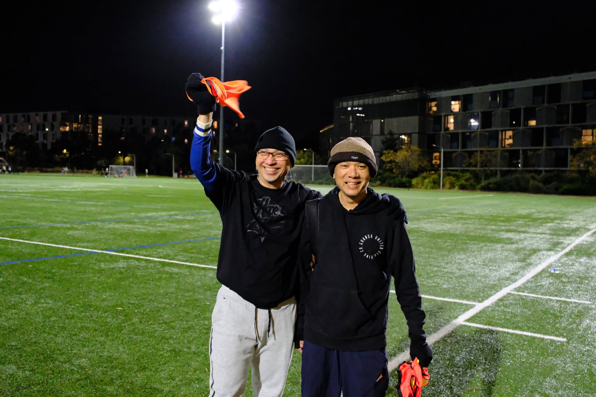 Two friends in black hoodies, one waving a bib