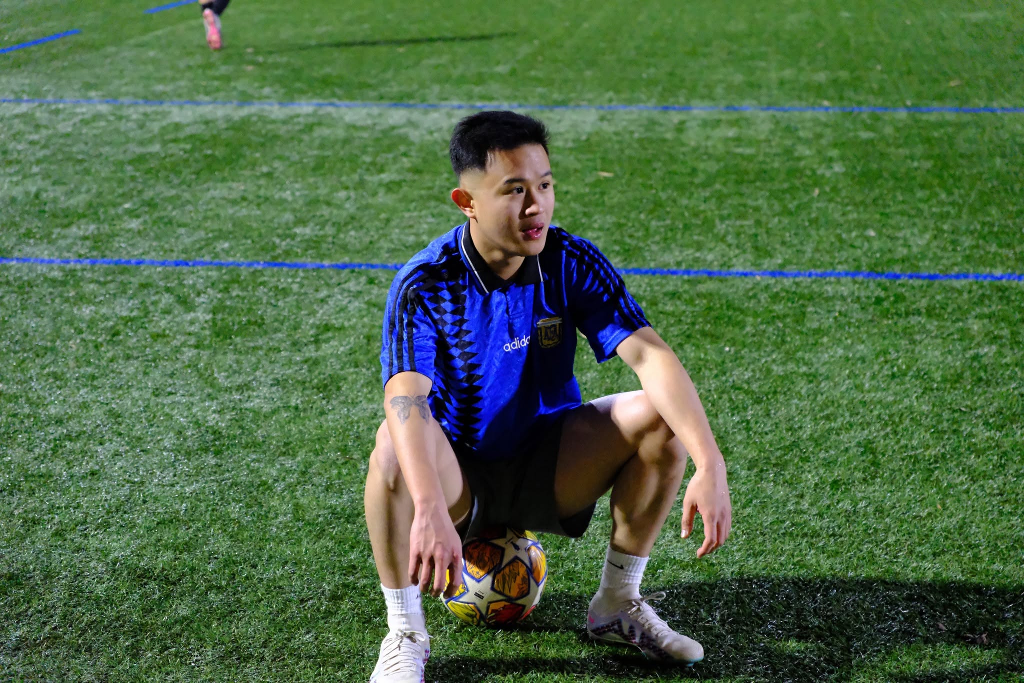 Player in a blue shirt crouching on top of a ball