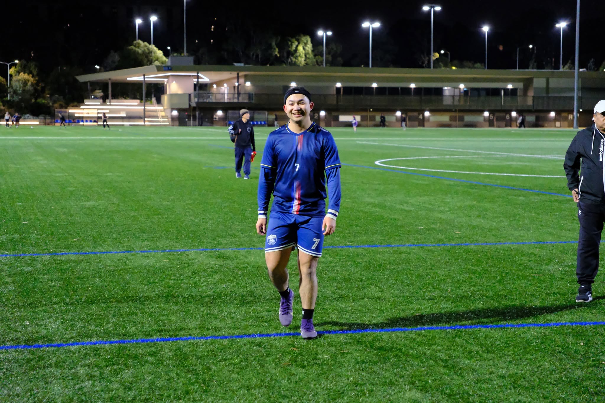 Smiling player in a blue kit walking back across the pitch