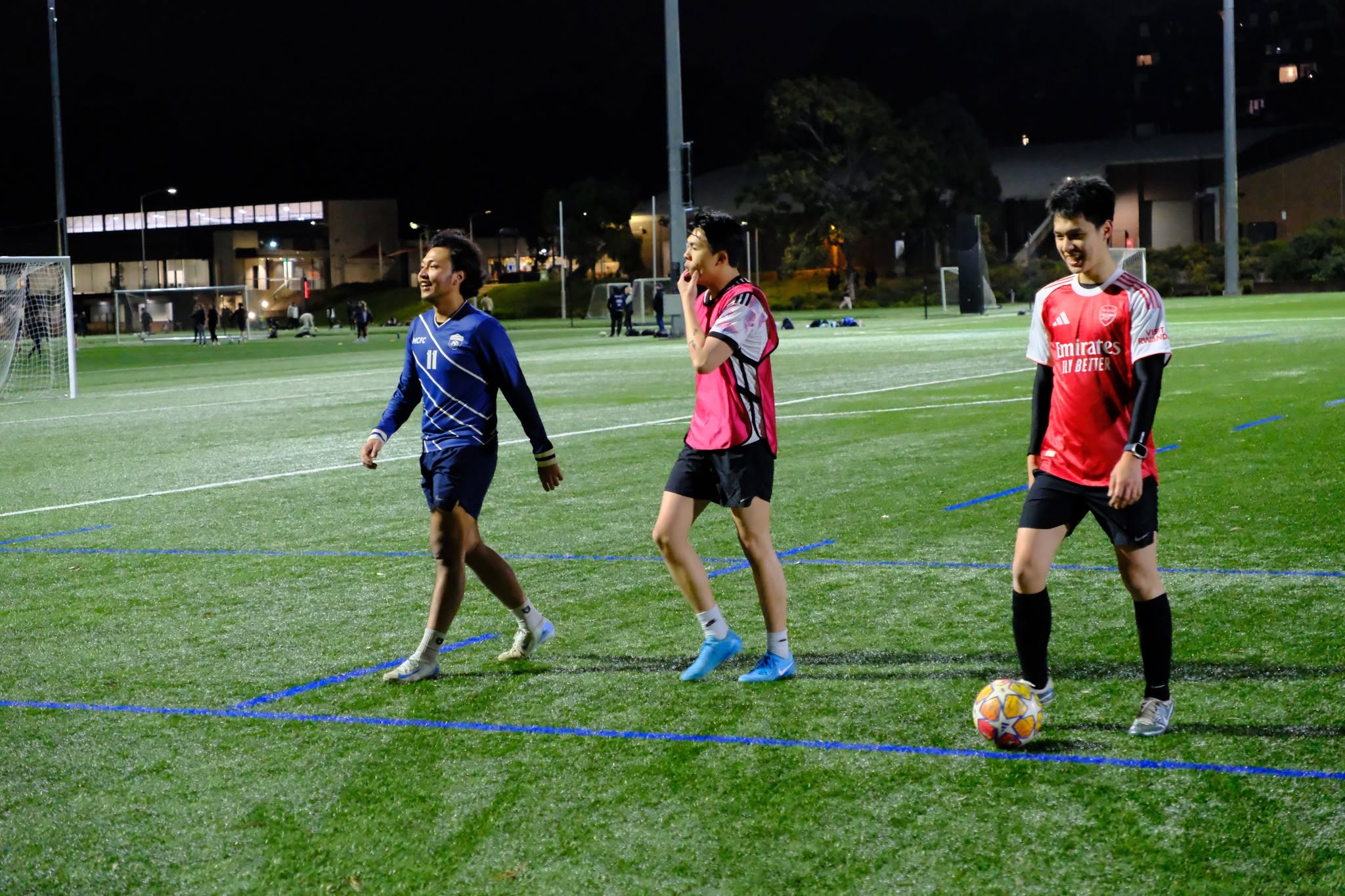 Players in blue and red shirts chasing the ball at night