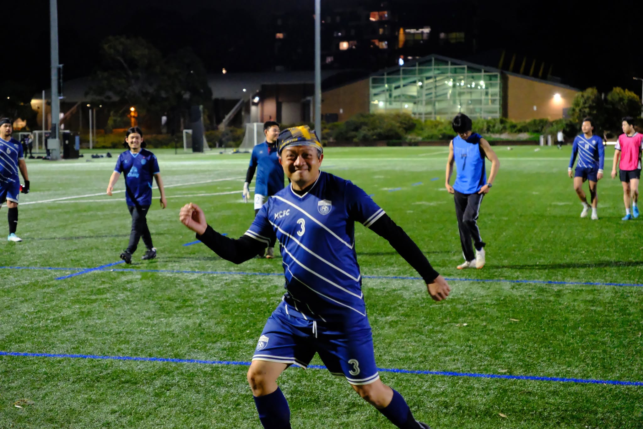A player in a blue number 3 shirt running hard with teammates behind