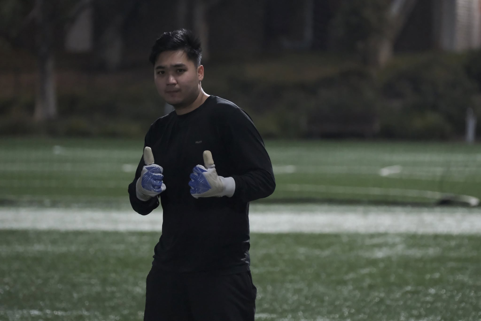Goalkeeper in black and gloves giving two thumbs up