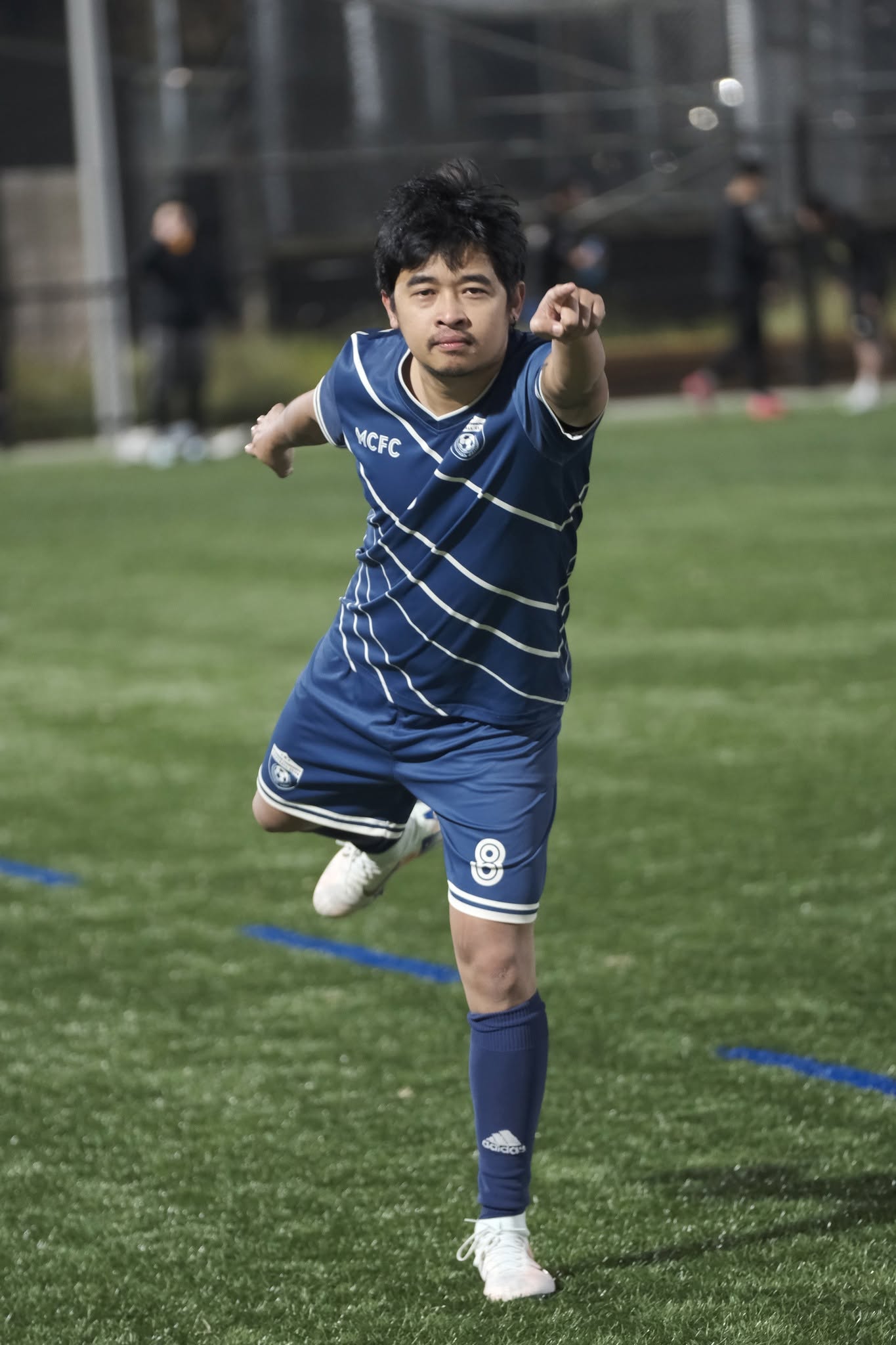 Player in a blue striped shirt pointing mid-stride