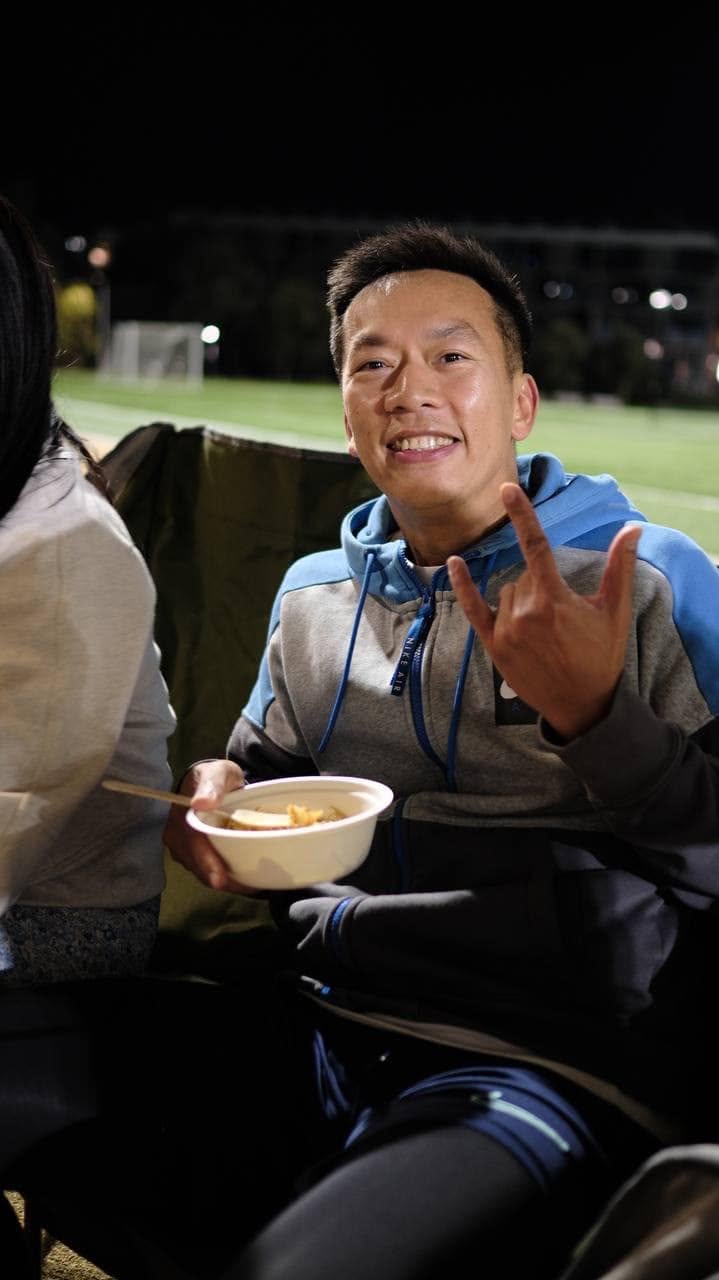Player in a hoodie holding a bowl of food and throwing a rock-on sign